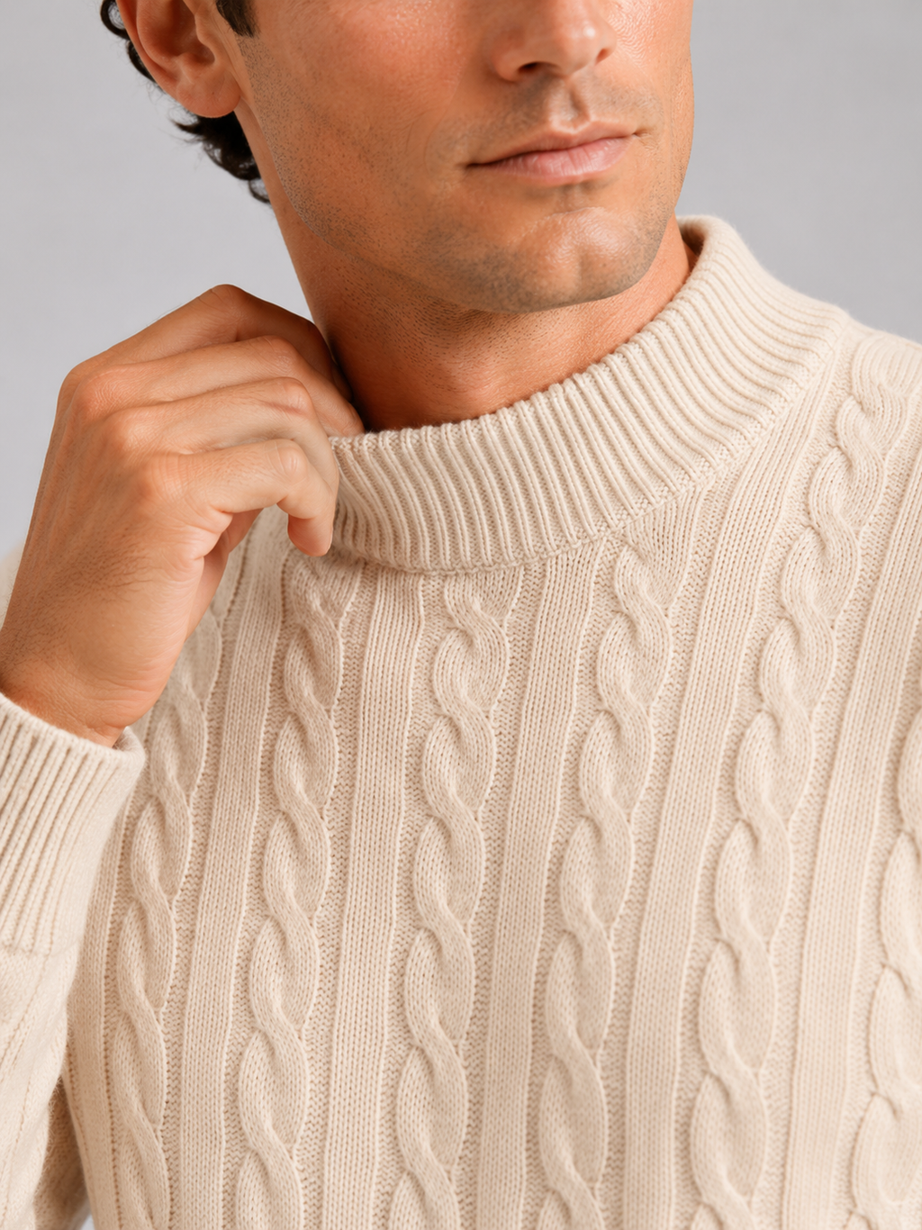 Close up of beige wool cable knit sweater showing soft texture and mock neck detail