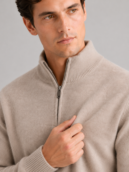 Close up of beige wool half zip sweater showing thick knit texture and refined zipper detail