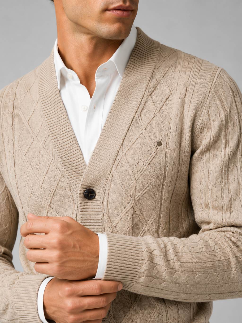 Close up of beige argyle cardigan showing cable knit texture and refined button front detail