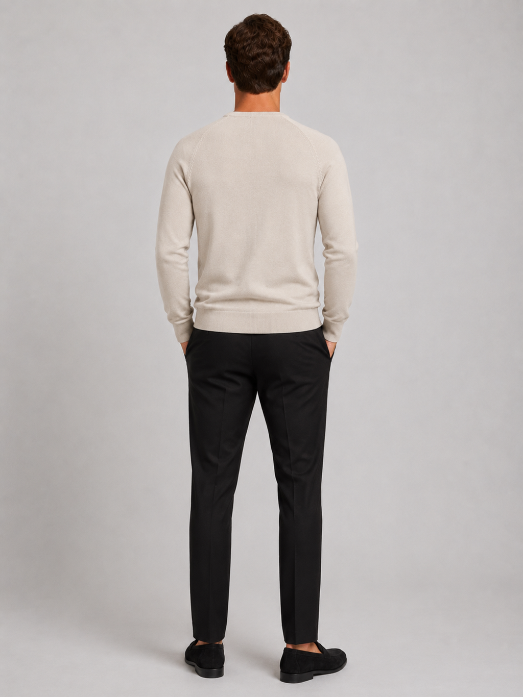 Back view of a man wearing a beige argyle sweater showing the crew neck, long sleeves, and comfortable fit