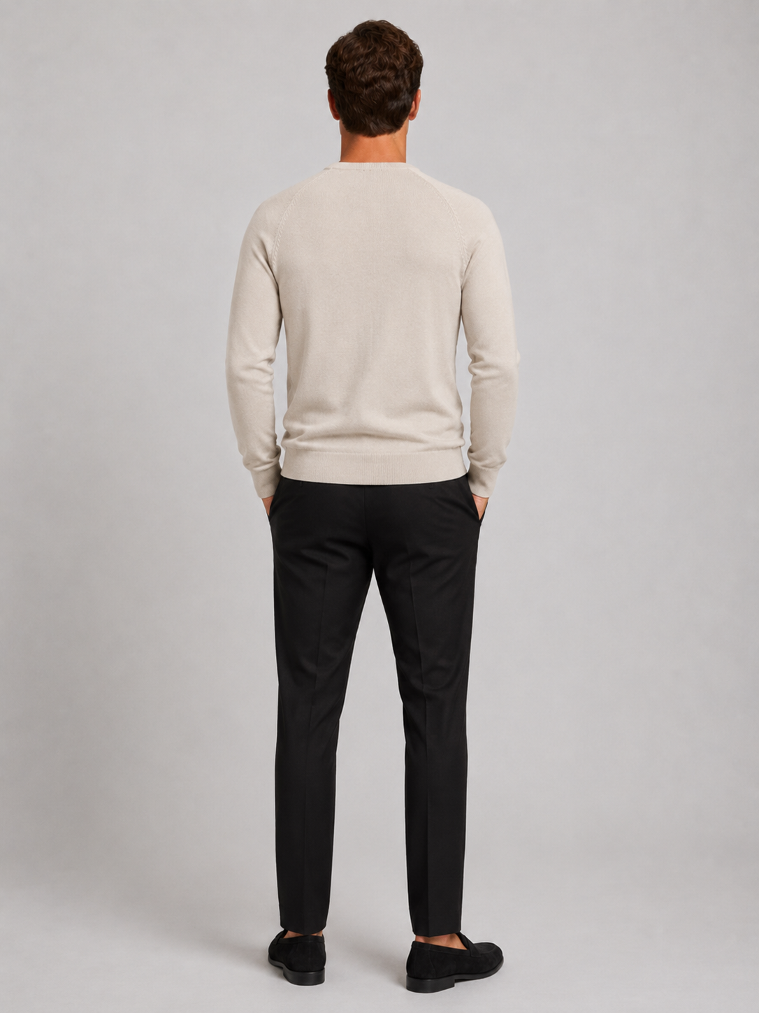 Back view of a man wearing a beige argyle sweater showing the crew neck, long sleeves, and comfortable fit