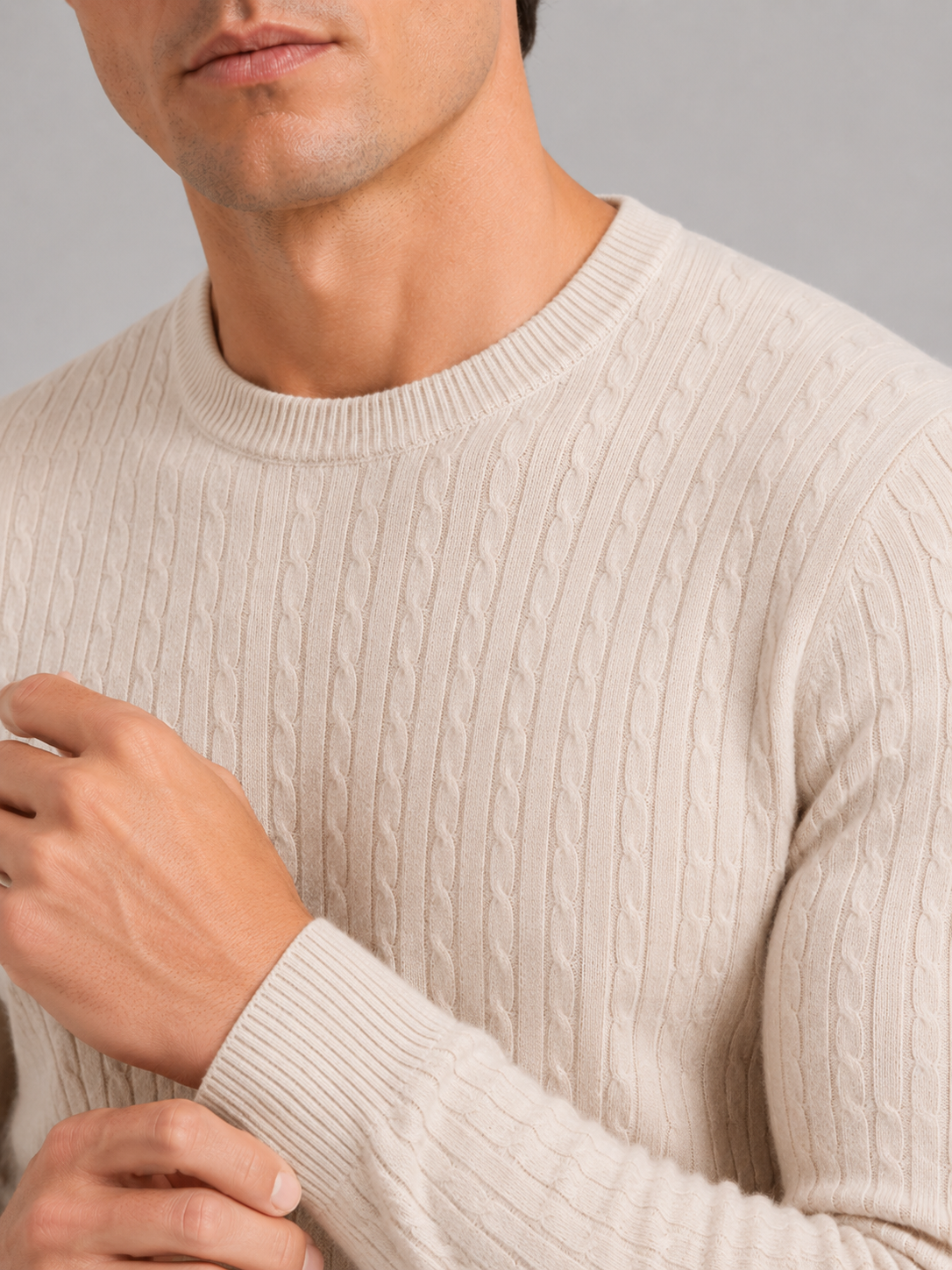 Close up of beige cable knit sweater showing soft textured fabric and clean crew neck detail