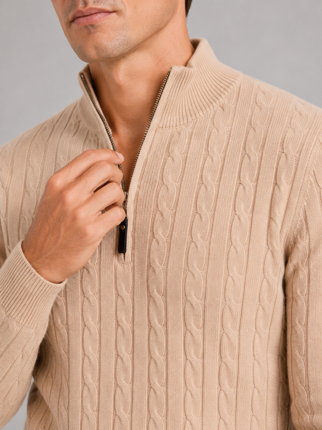 Close up of beige cable knit sweater showing thick textured fabric and quarter zip detail