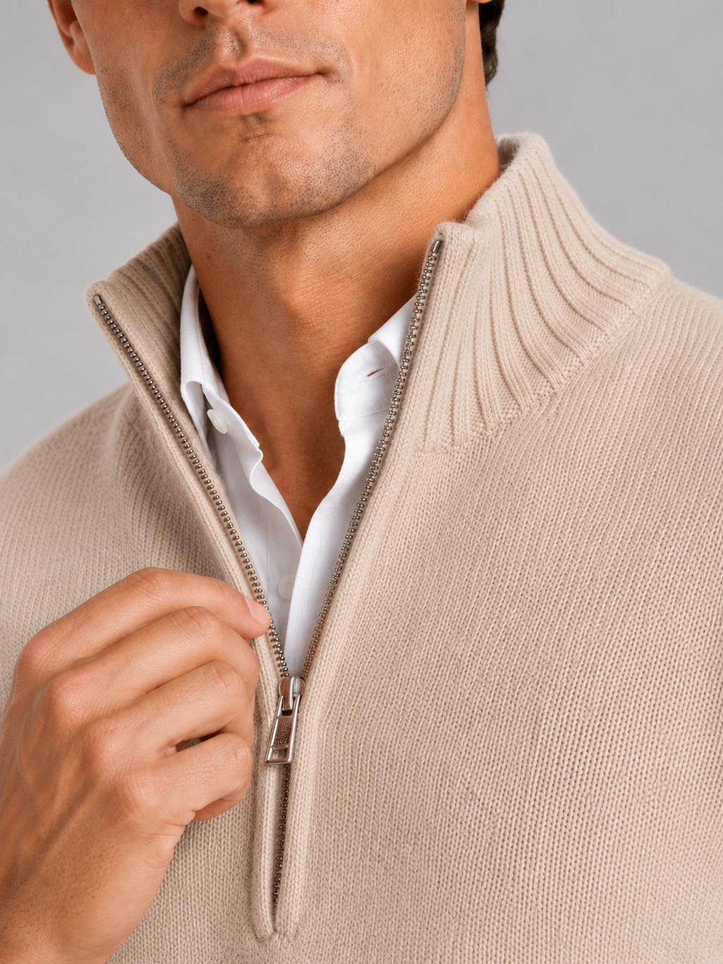 Close up of beige half zip sweater showing soft knit texture and refined zipper detail