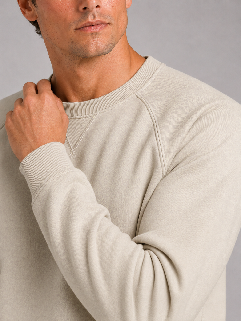 Close up of beige cotton sweater showing heavyweight knit fabric and classic crew neck detail