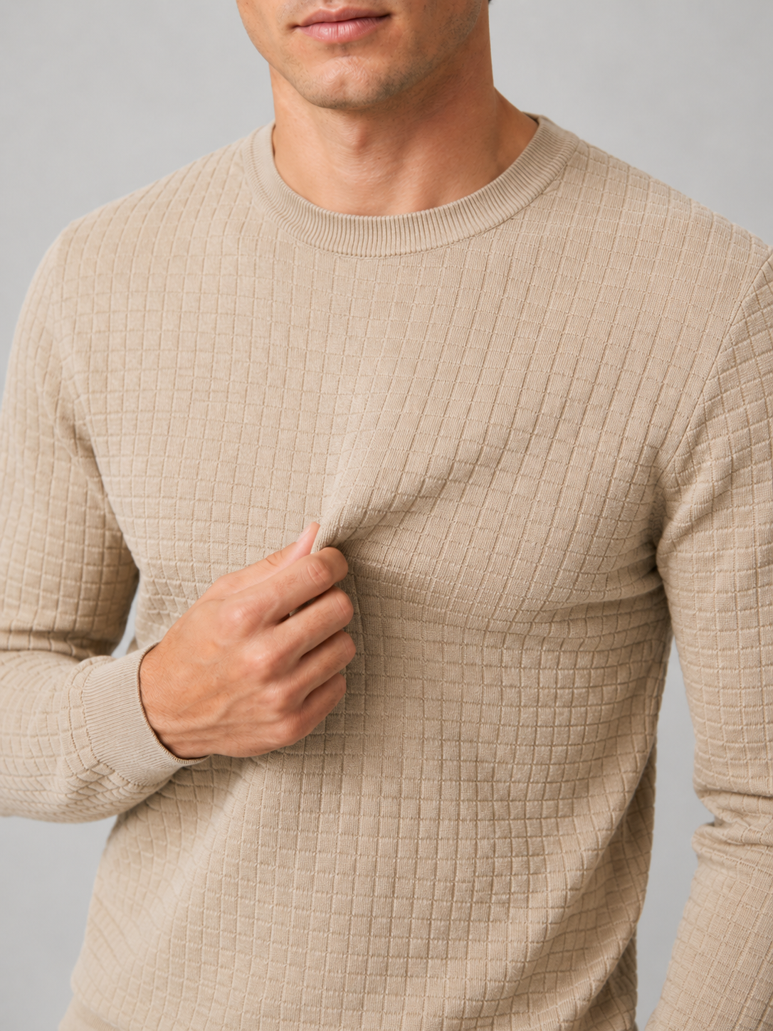 Close up of beige jacquard sweater showing textured knit pattern and classic crew neck detail