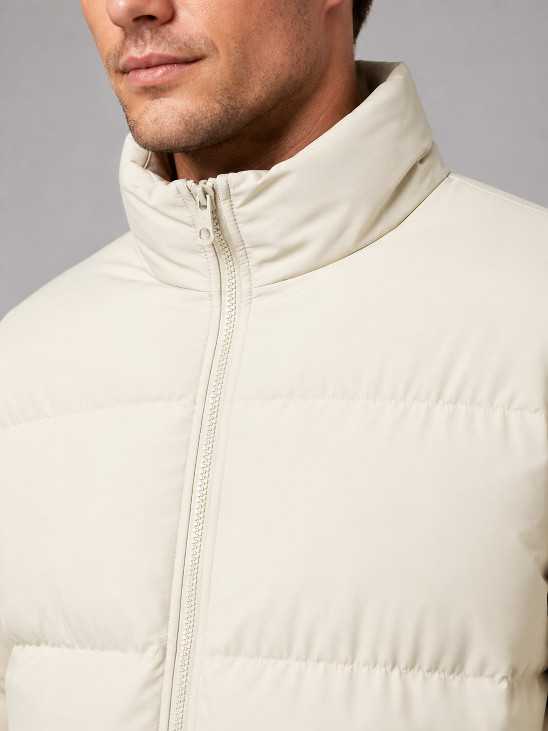Close up of beige puffer jacket showing insulated quilted construction and stand collar detail