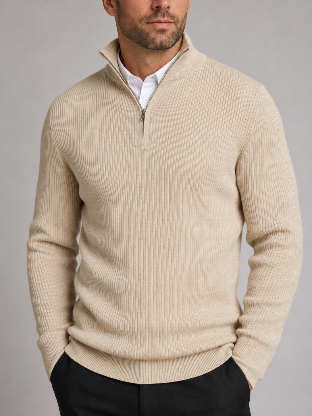 Close-up of a beige quarter zip sweater showing the warm knit texture, mock neck, zipper, cuffs, and stitching