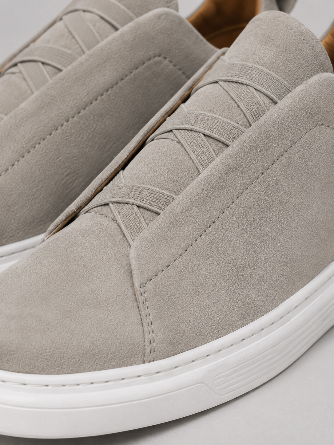 Close up of beige suede slip on sneakers showing soft suede texture and clean stitching detail