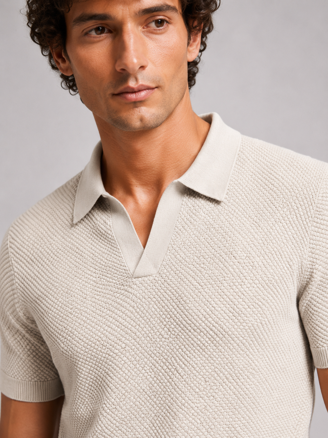 Close up of beige knit polo showing soft breathable stretch fabric and refined collar detail