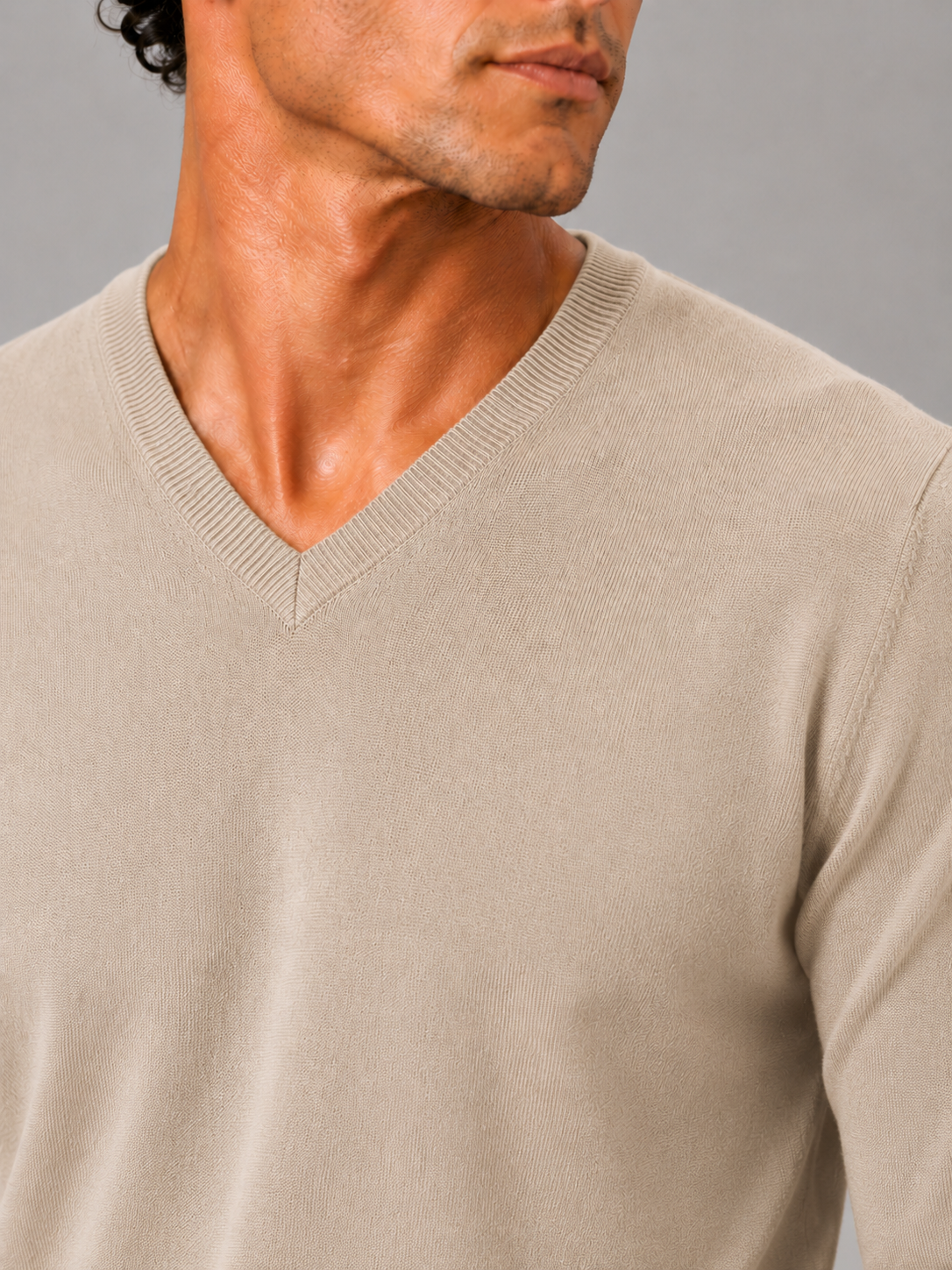 Close up of beige knit sweater showing soft lightweight fabric and refined v neck detail