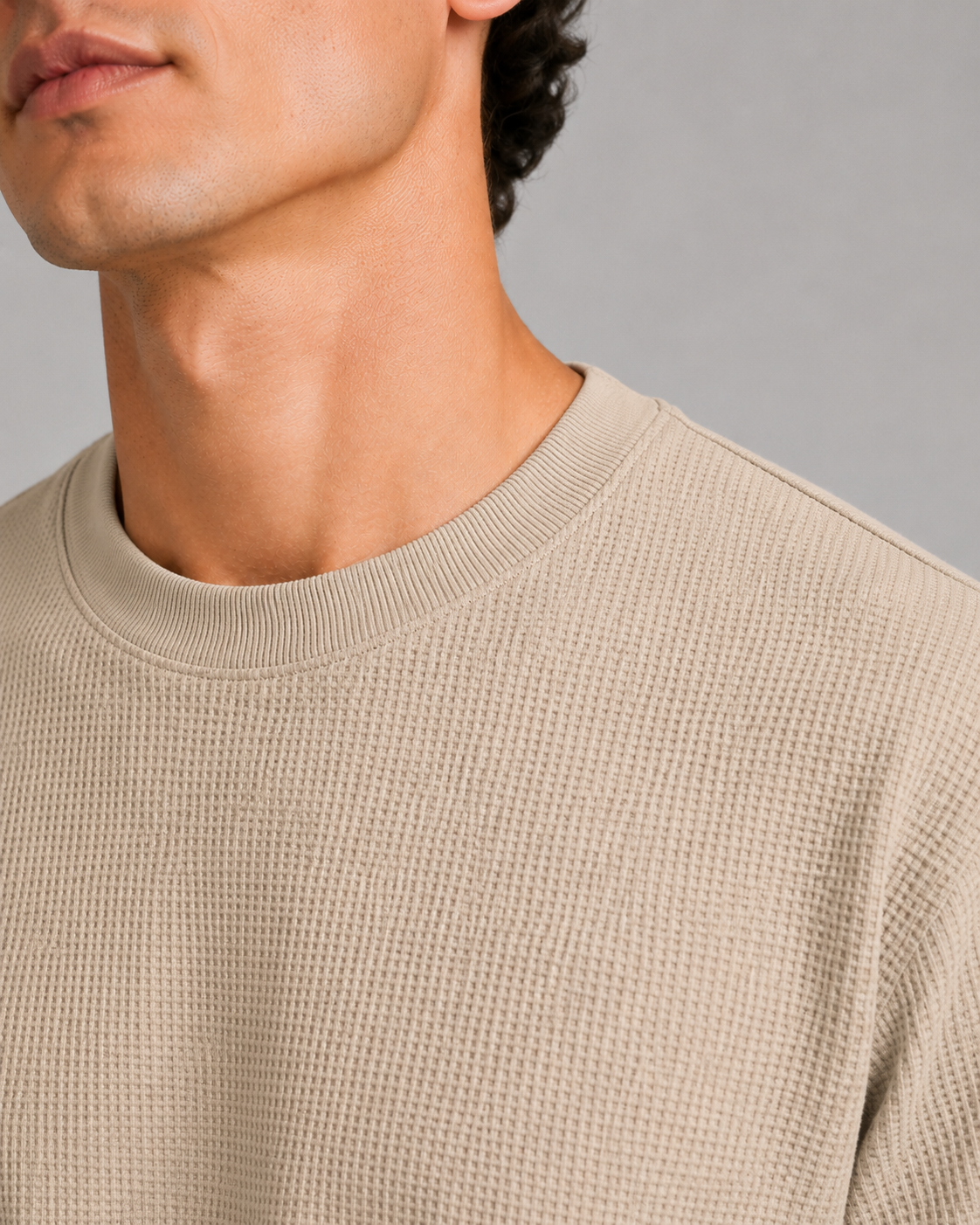 Close up of beige waffle knit fabric showing soft breathable textured weave and lightweight finish