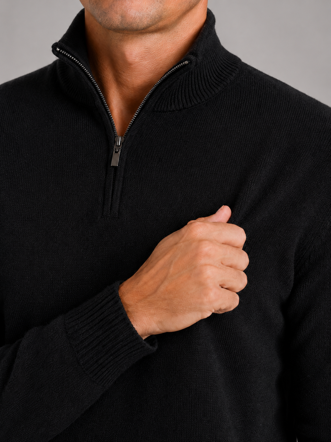 Close up of black wool half zip sweater showing thick knit texture and refined zipper detail