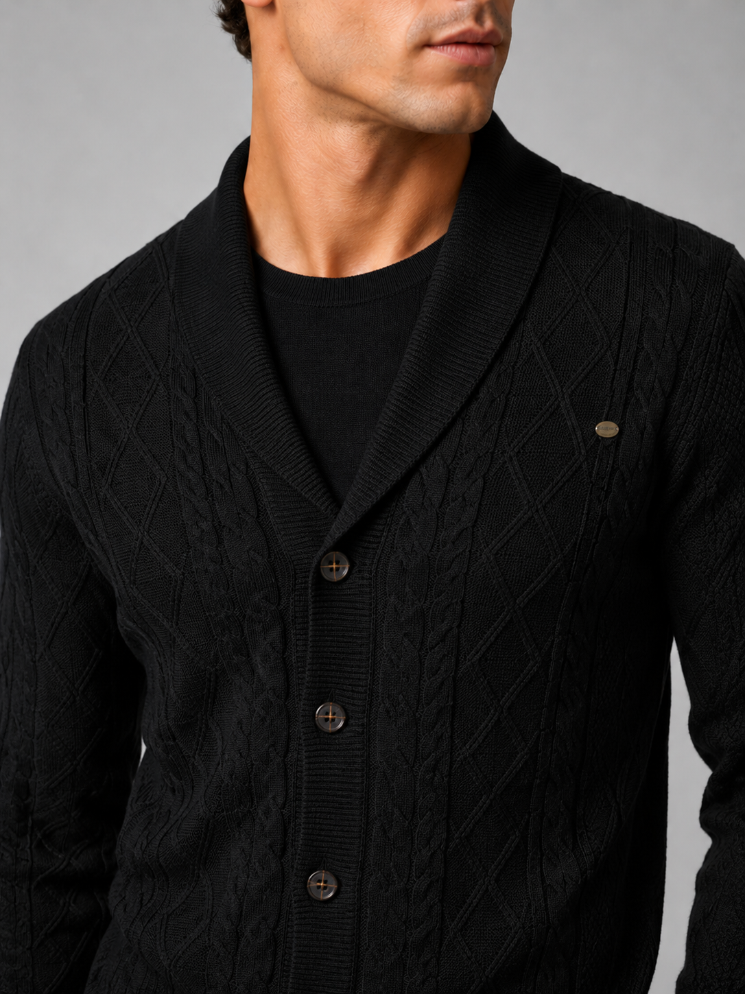Close up of black argyle cardigan showing cable knit texture and refined button front detail