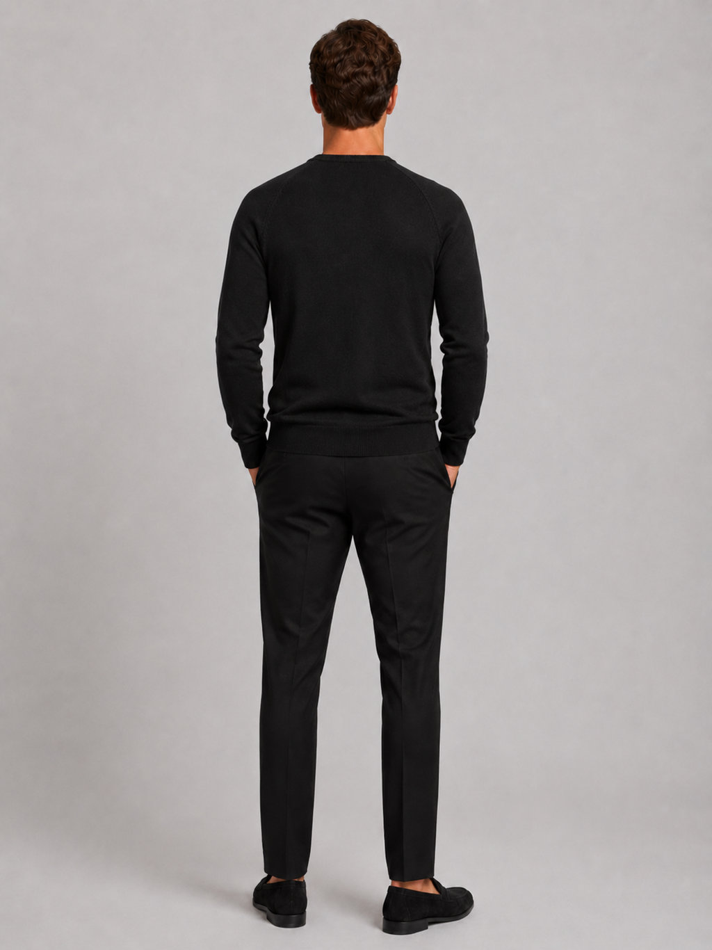 Back view of a man wearing a black argyle sweater showing the crew neck, long sleeves, and comfortable fit
