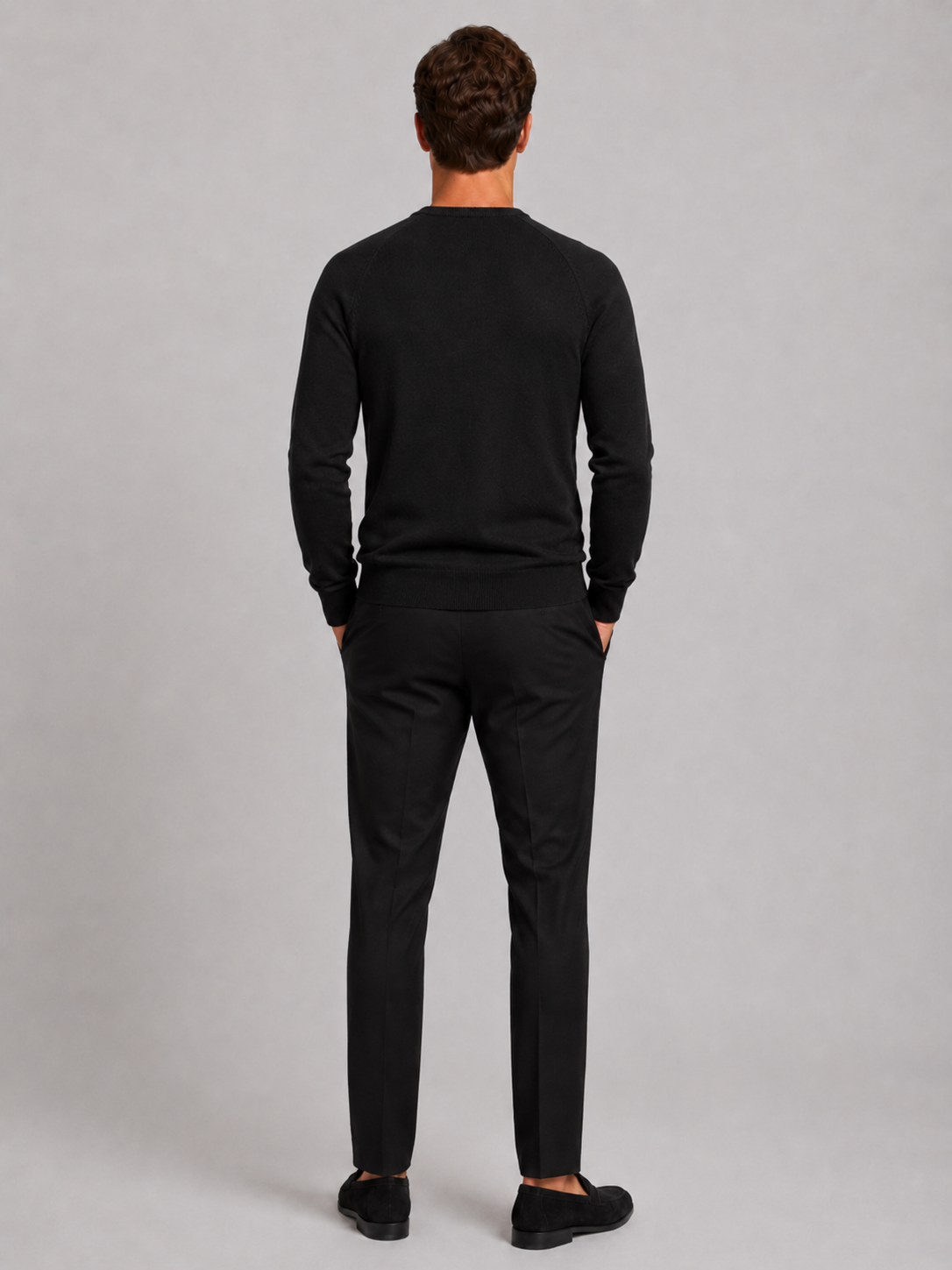 Back view of a man wearing a black argyle sweater showing the crew neck, long sleeves, and comfortable fit