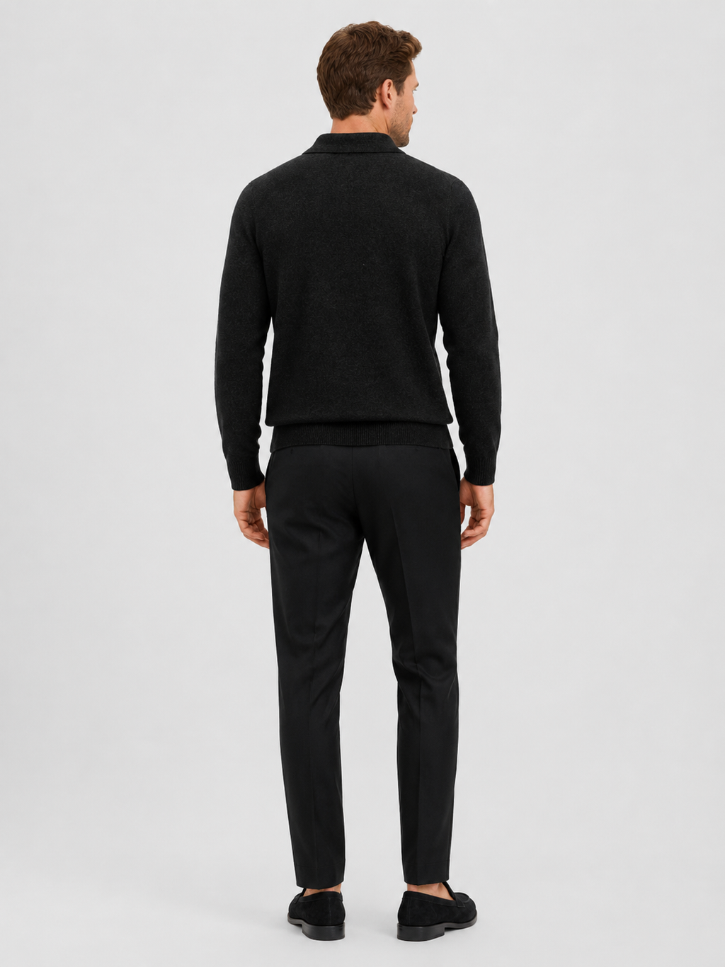 Back view of a man wearing a black argyle sweater showing the solid knit back, long sleeves, and comfortable fit