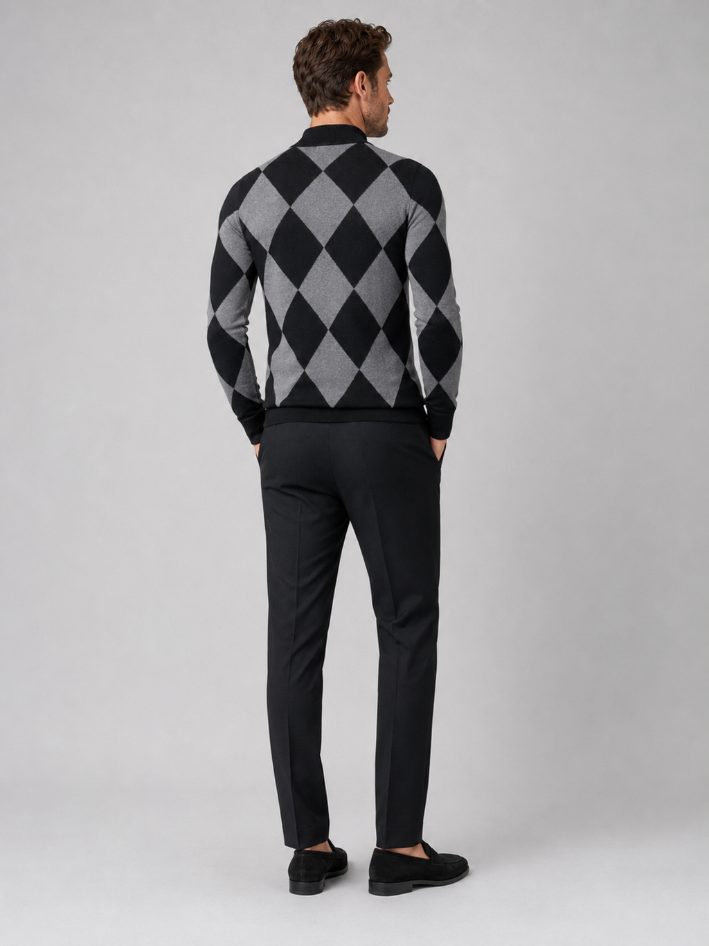 Back view of a man wearing a black argyle turtleneck sweater showing the slim fit, long sleeves, and warm knit fabric