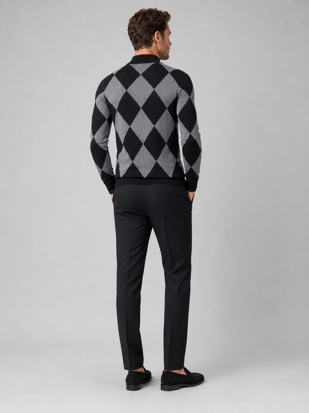 Back view of a man wearing a black argyle turtleneck sweater showing the slim fit, long sleeves, and warm knit fabric