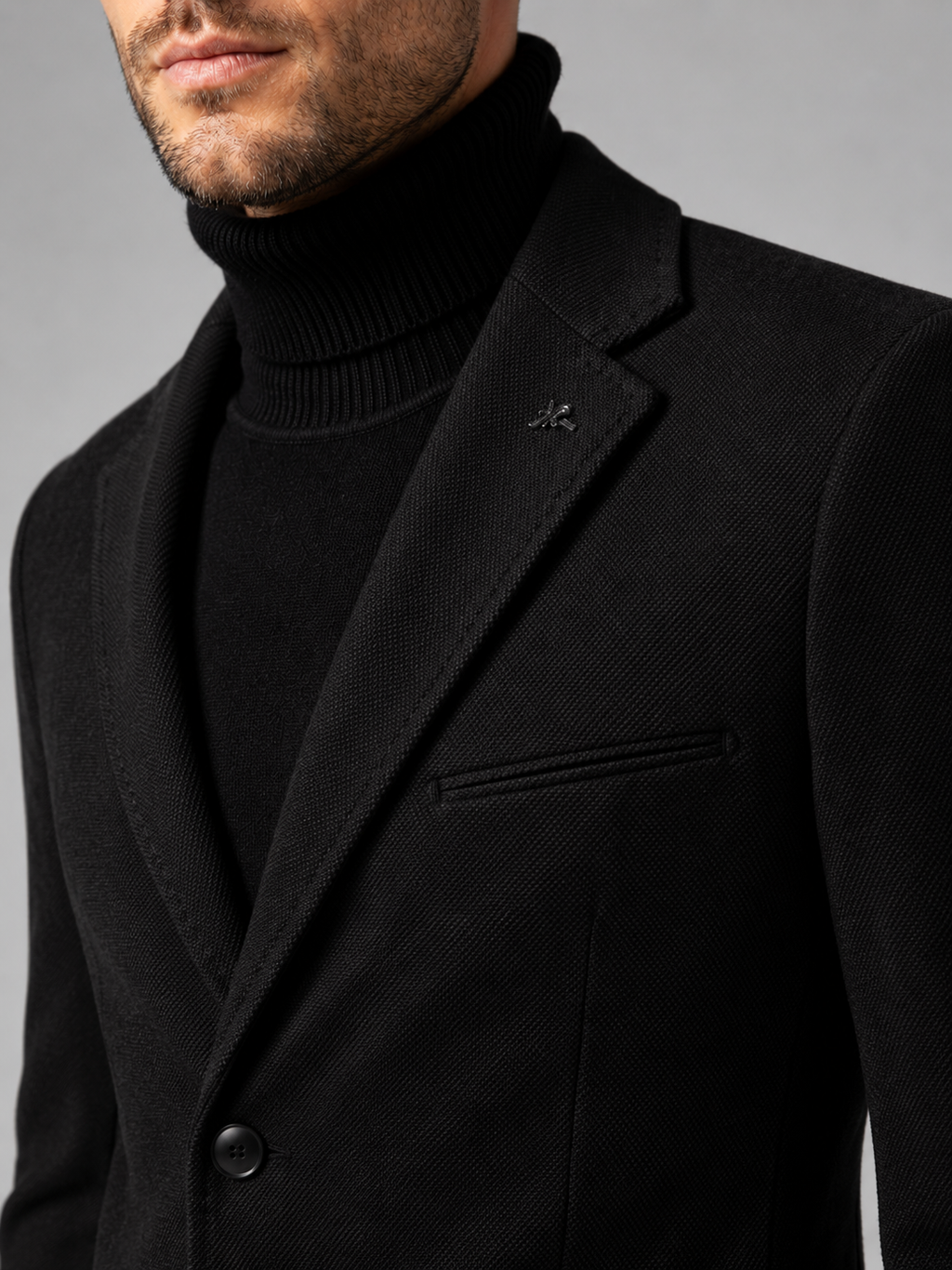Close up of black blazer showing tailored construction, notch lapel, and single breasted button detail