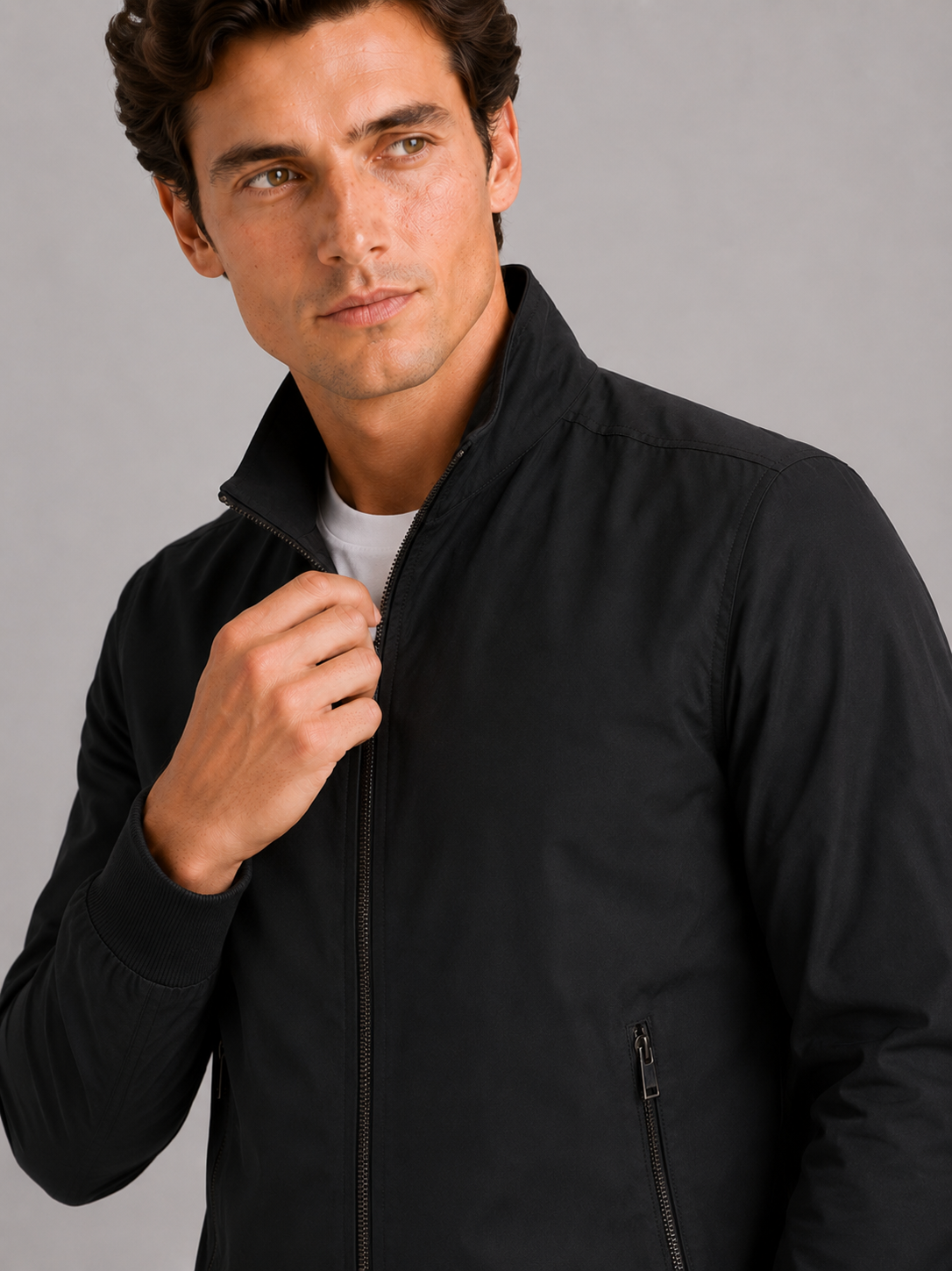Close up of black bomber jacket showing smooth fabric and refined zipper collar detail