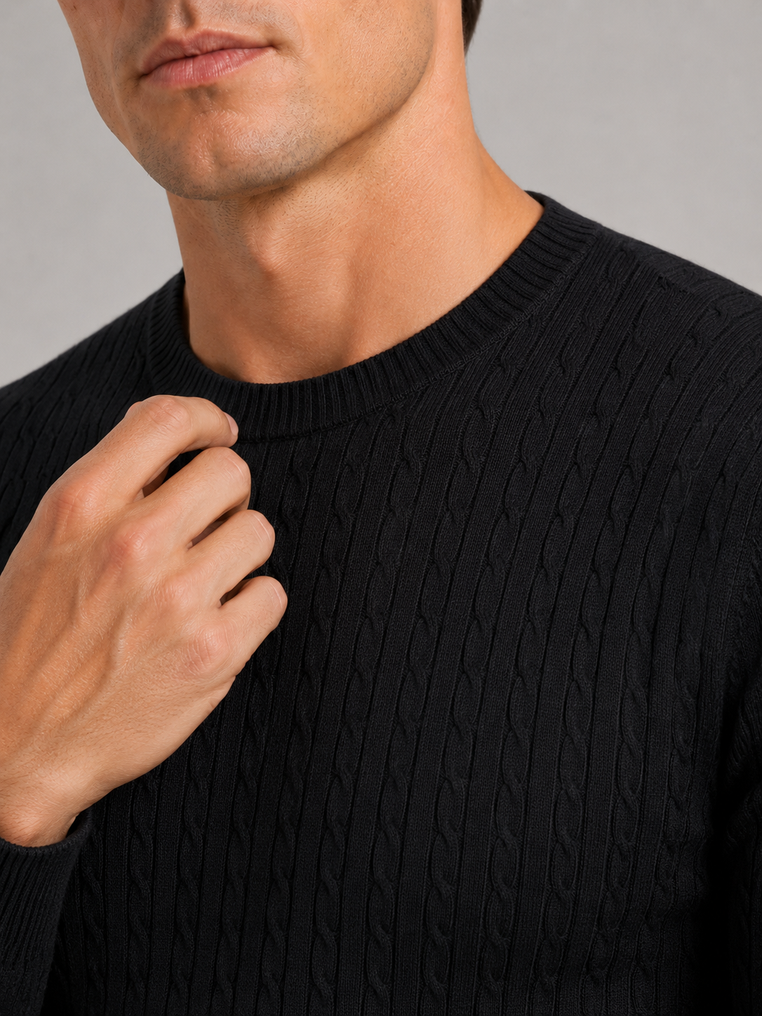 Close up of black cable knit sweater showing soft textured fabric and clean crew neck detail
