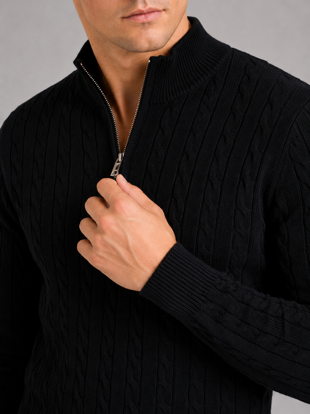 Close up of black cable knit sweater showing thick textured fabric and quarter zip detail