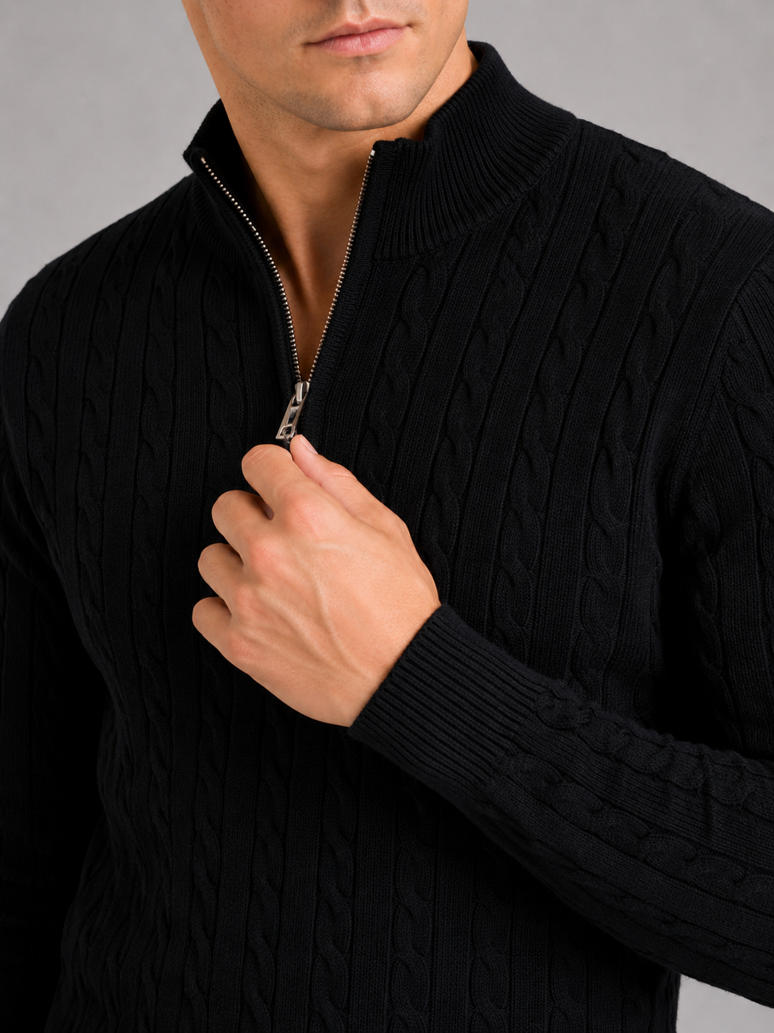 Close up of black cable knit sweater showing thick textured fabric and quarter zip detail