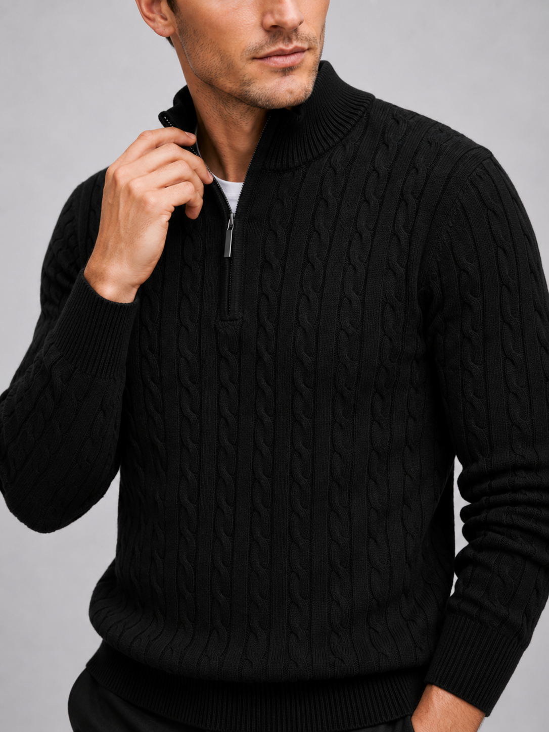 Close up of black cable knit sweater showing textured pattern, mock neck, and quarter zip detail