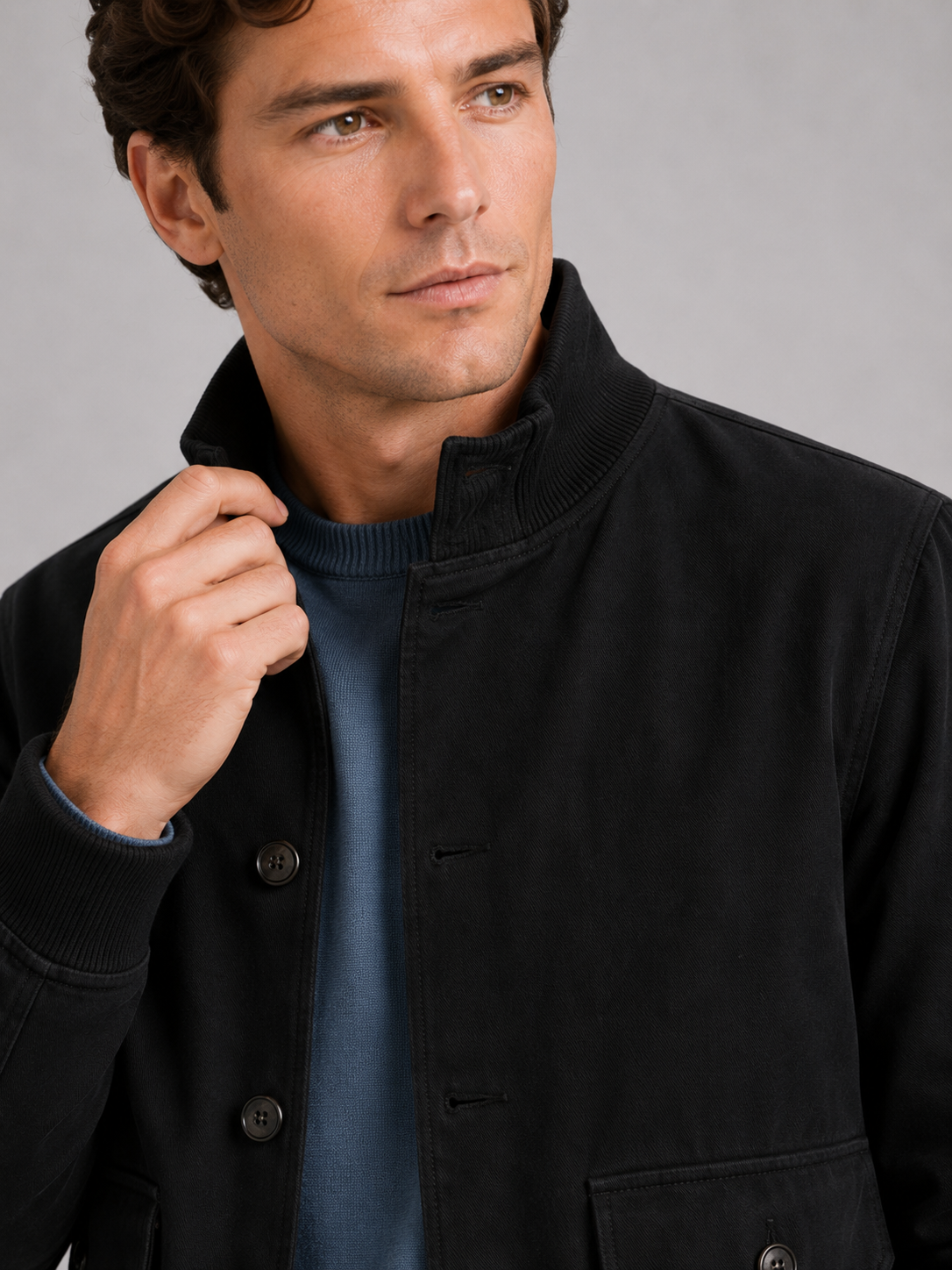 Close up of black cargo jacket showing patchwork design, ribbed trim, and durable fabric detail