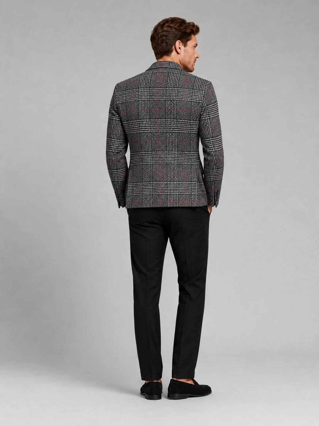 Back view of a man wearing a black checkered blazer showing the tailored slim fit, structured shoulders, and clean back design