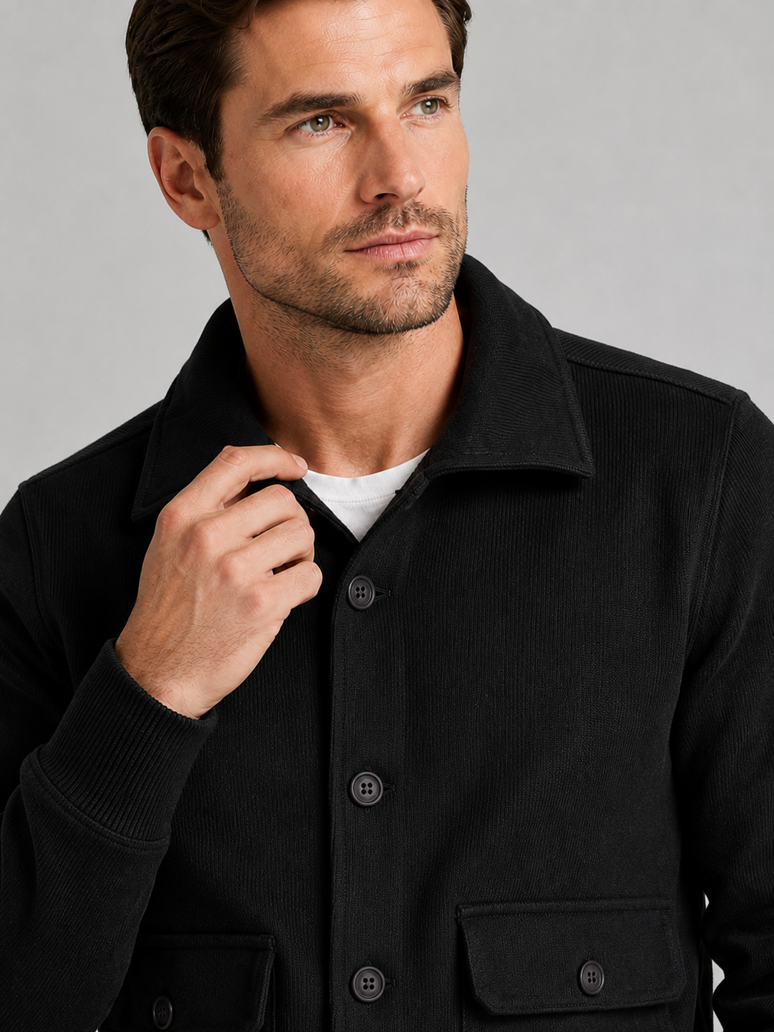 Close up of black chore jacket showing durable fabric, button up front, and utility pocket detail