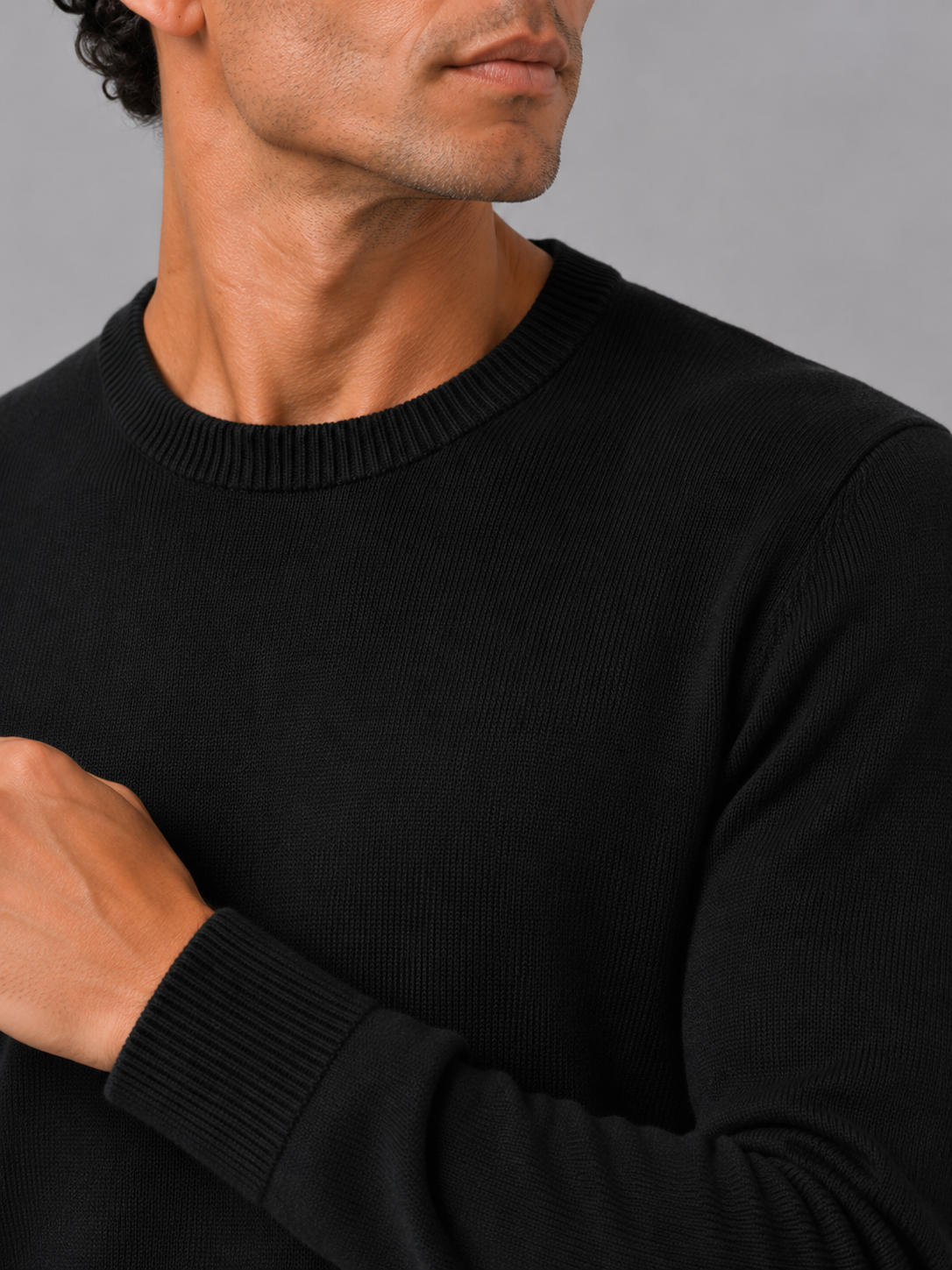 Close up of black knit sweater showing soft lightweight fabric and clean crew neck detail
