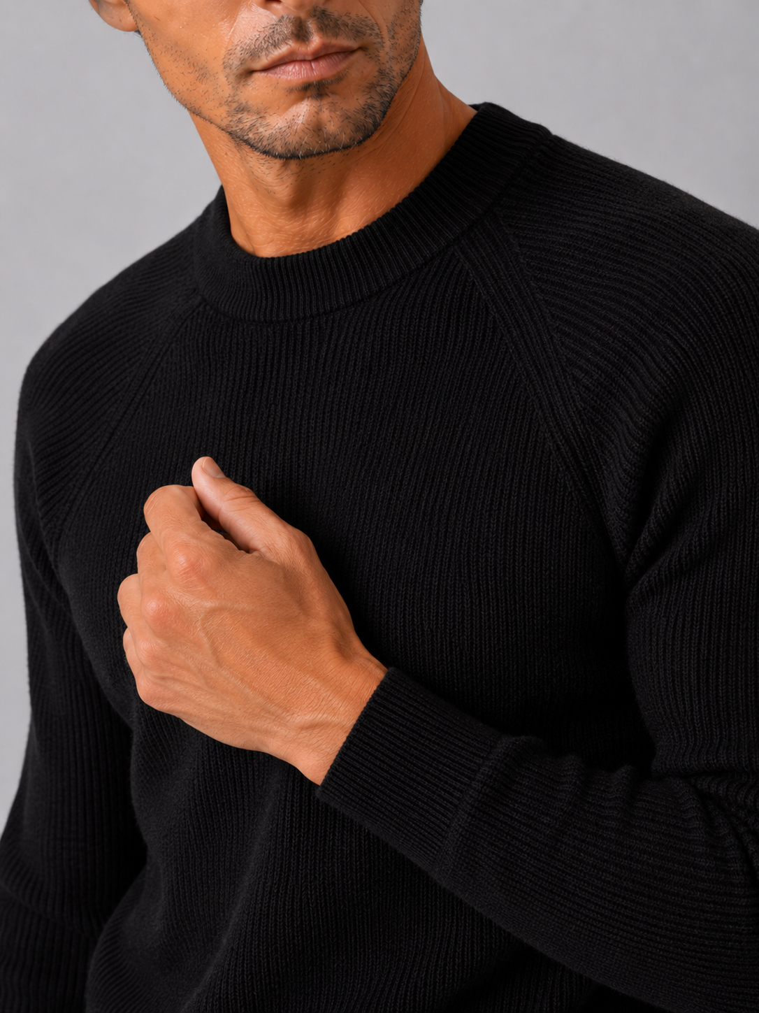 Close up of black knit sweater showing thick soft fabric and classic crew neck detail