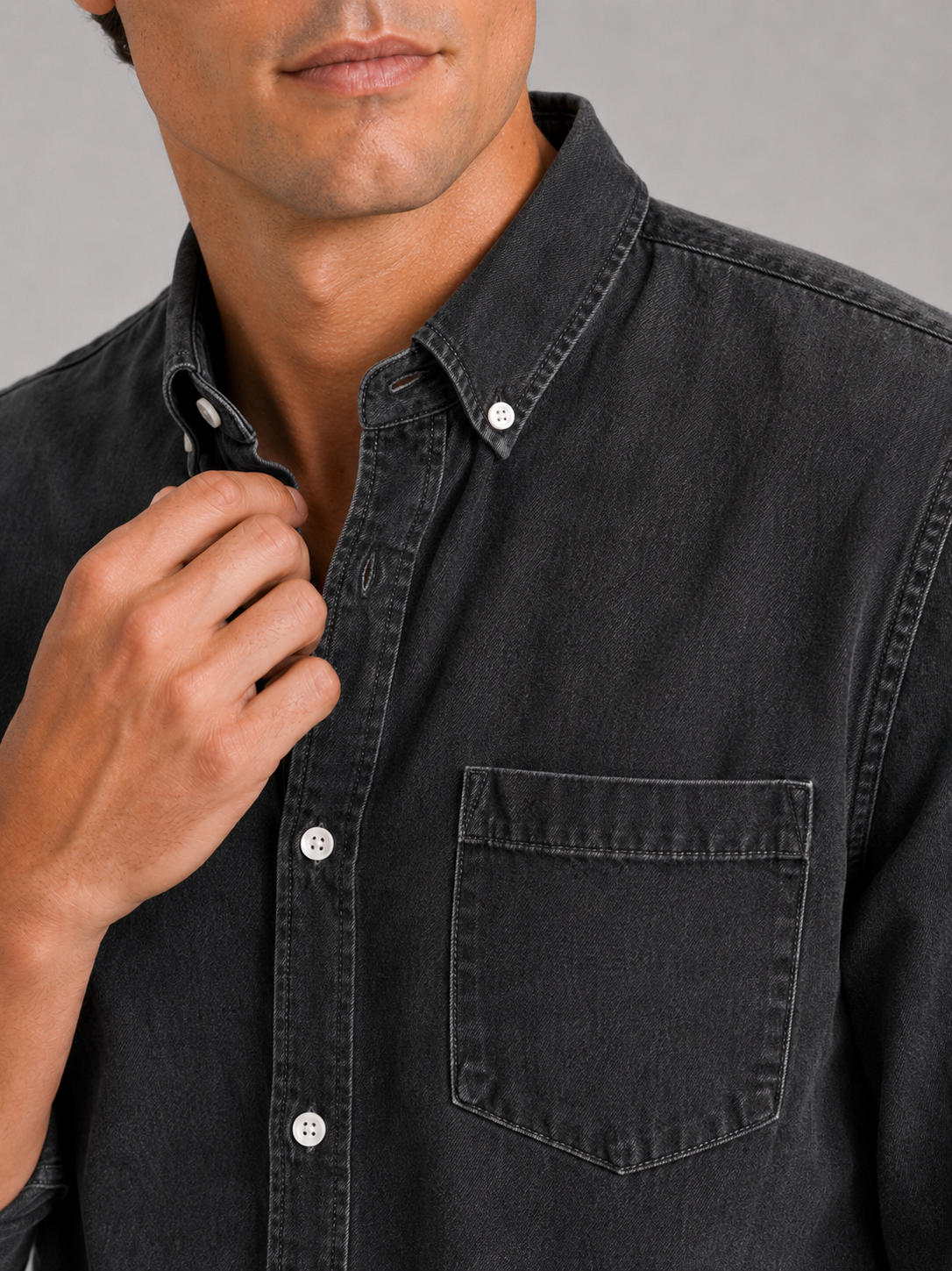Close up of black denim shirt showing washed fabric texture and button down detail