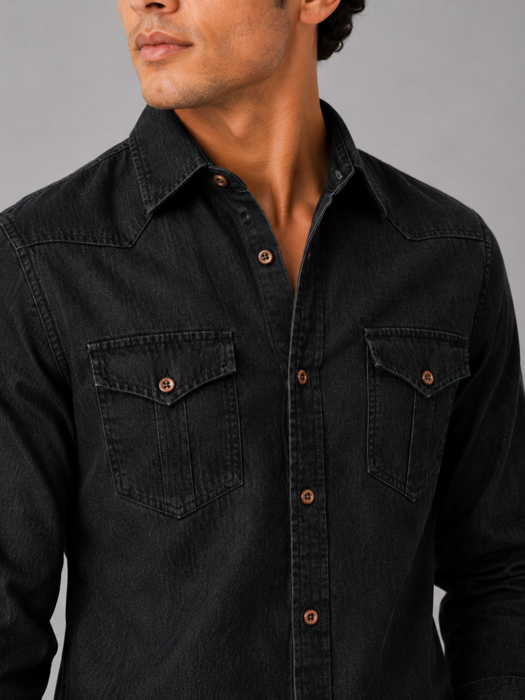 Close up of black denim shirt showing washed cotton texture and button up detail