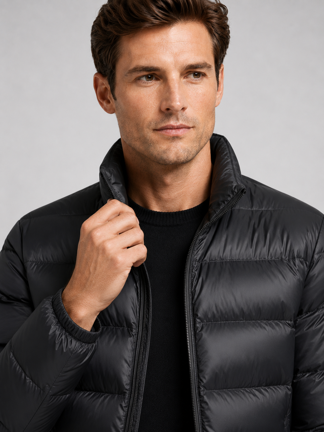 Close up of black down jacket showing lightweight quilted insulation, stand collar, and weather resistant fabric detail