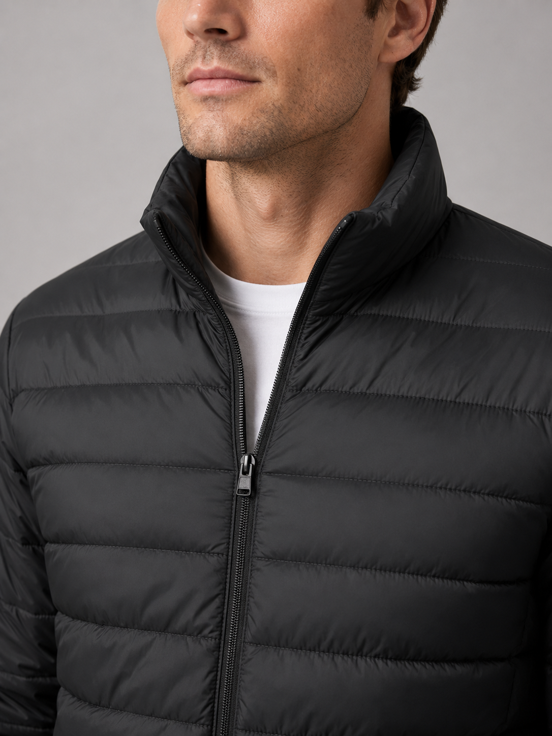 Close up of black down puffer jacket showing insulated quilting, stand collar, and weather resistant fabric detail