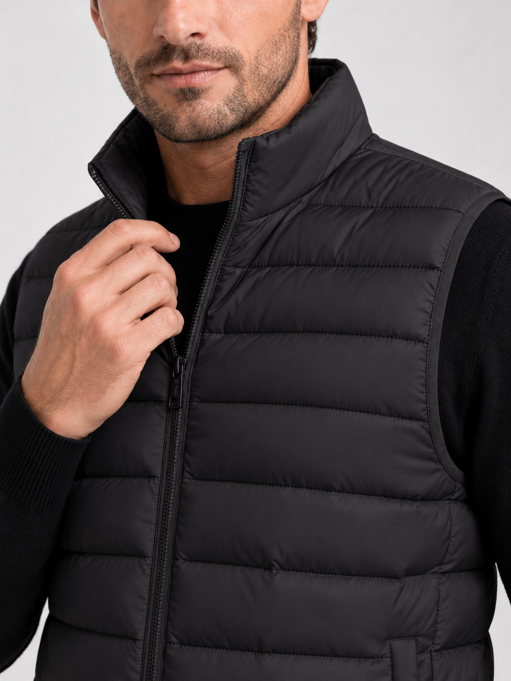 Close up of black down puffer vest showing thick quilted insulation, zip up front, and weather resistant fabric detail