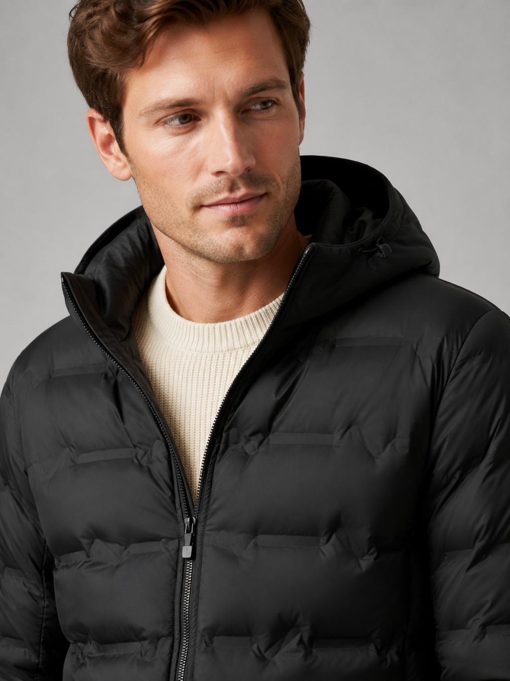 Close up of black duck down jacket showing lightweight quilted insulation, attached hood, and weather resistant fabric detail
