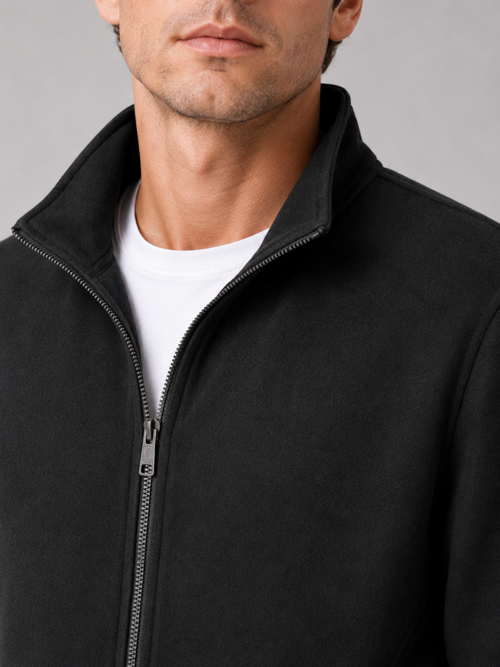 Close up of black workwear jacket showing durable fabric and stand collar zipper detail