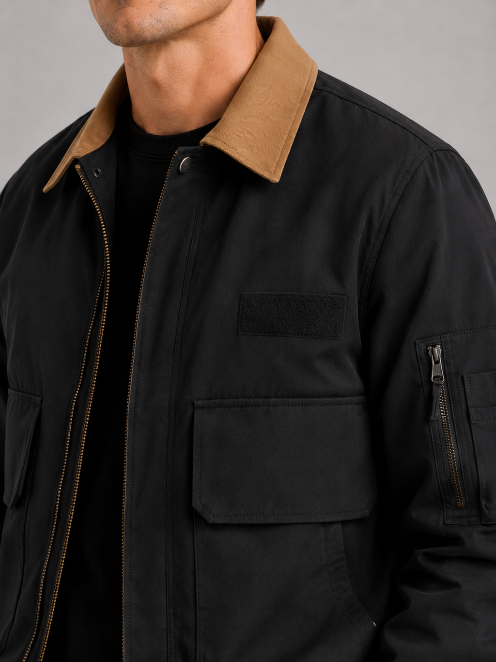 Close up of black military jacket showing durable cotton fabric and functional pocket detail