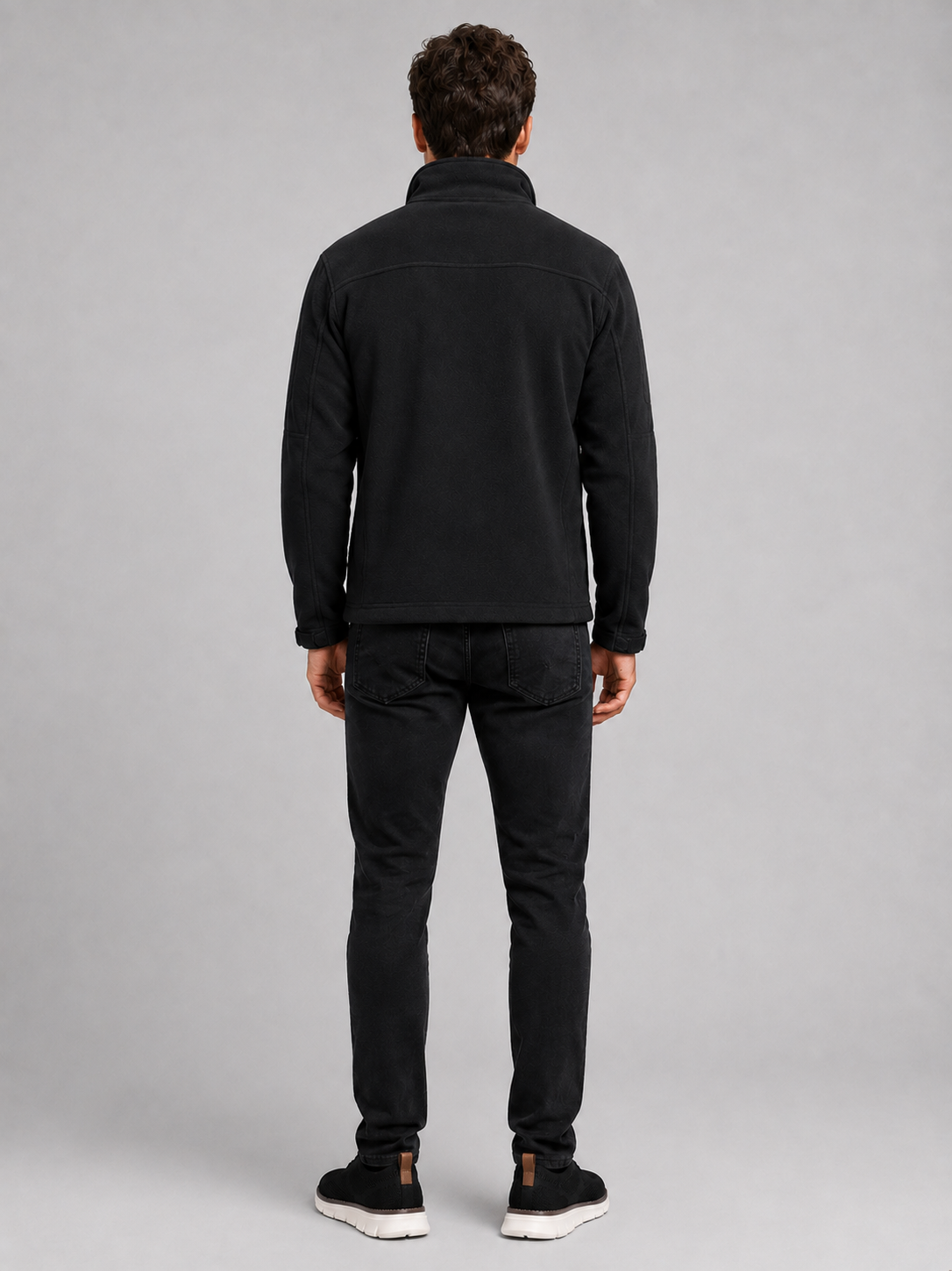 Back view of a man wearing a black fleece jacket showing the warm fleece construction, long sleeves, and comfortable outdoor fit