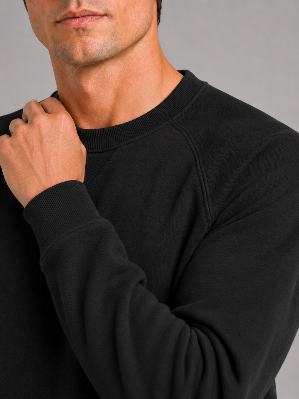 Close up of black cotton sweater showing heavyweight knit fabric and classic crew neck detail