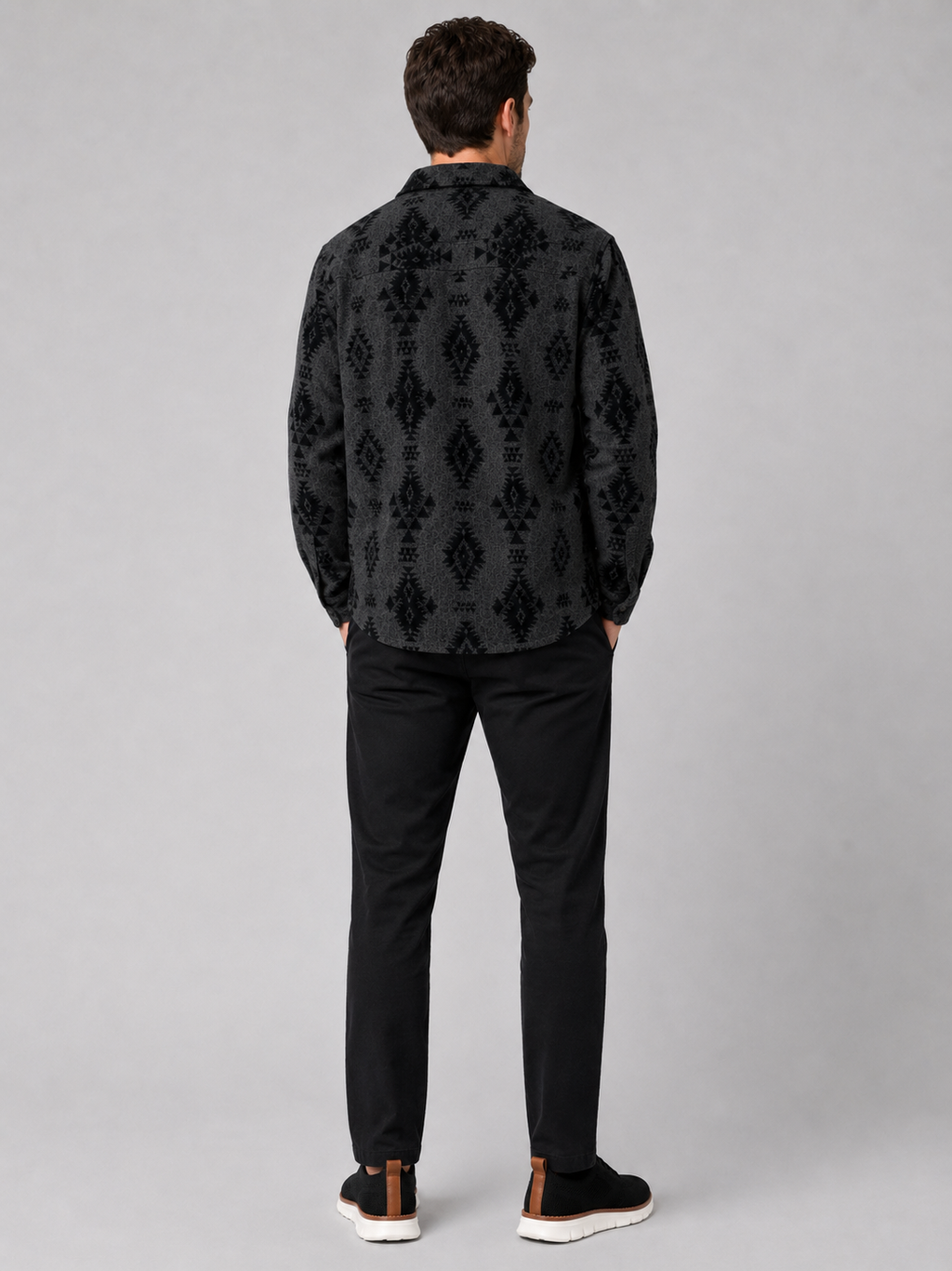 Back view of a man wearing a black heavyweight flannel jacket showing the relaxed fit, long sleeves, warm brushed fabric, and classic shacket silhouette