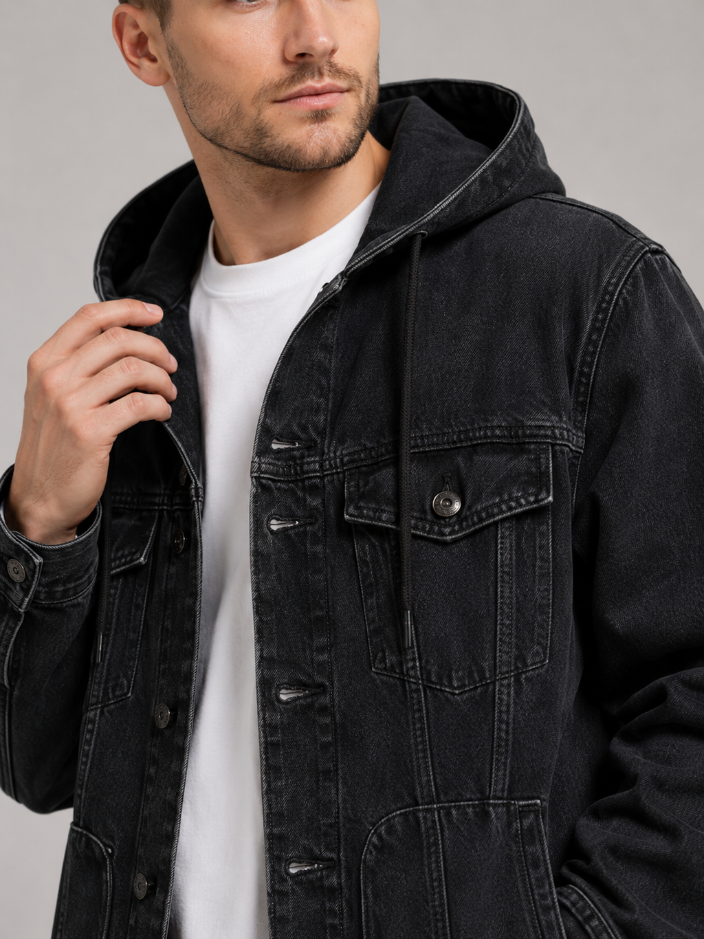Close up of black hooded denim jacket showing durable fabric, large utility pockets, and hood detail