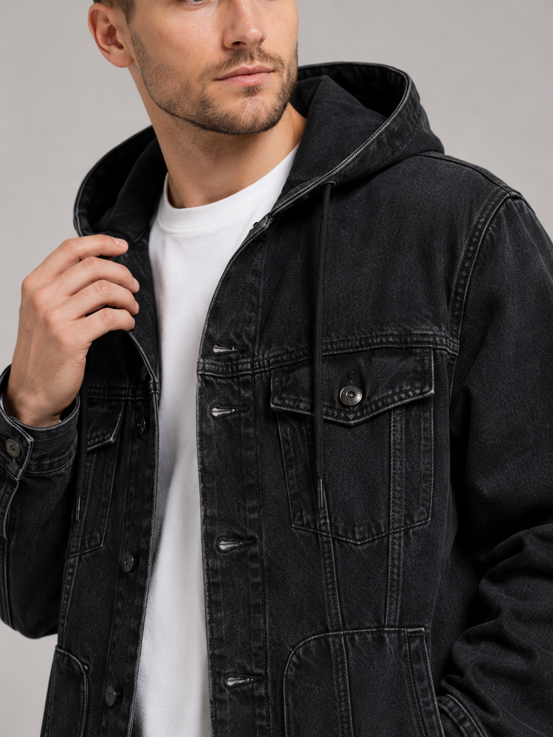 Close up of black hooded denim jacket showing durable fabric, large utility pockets, and hood detail