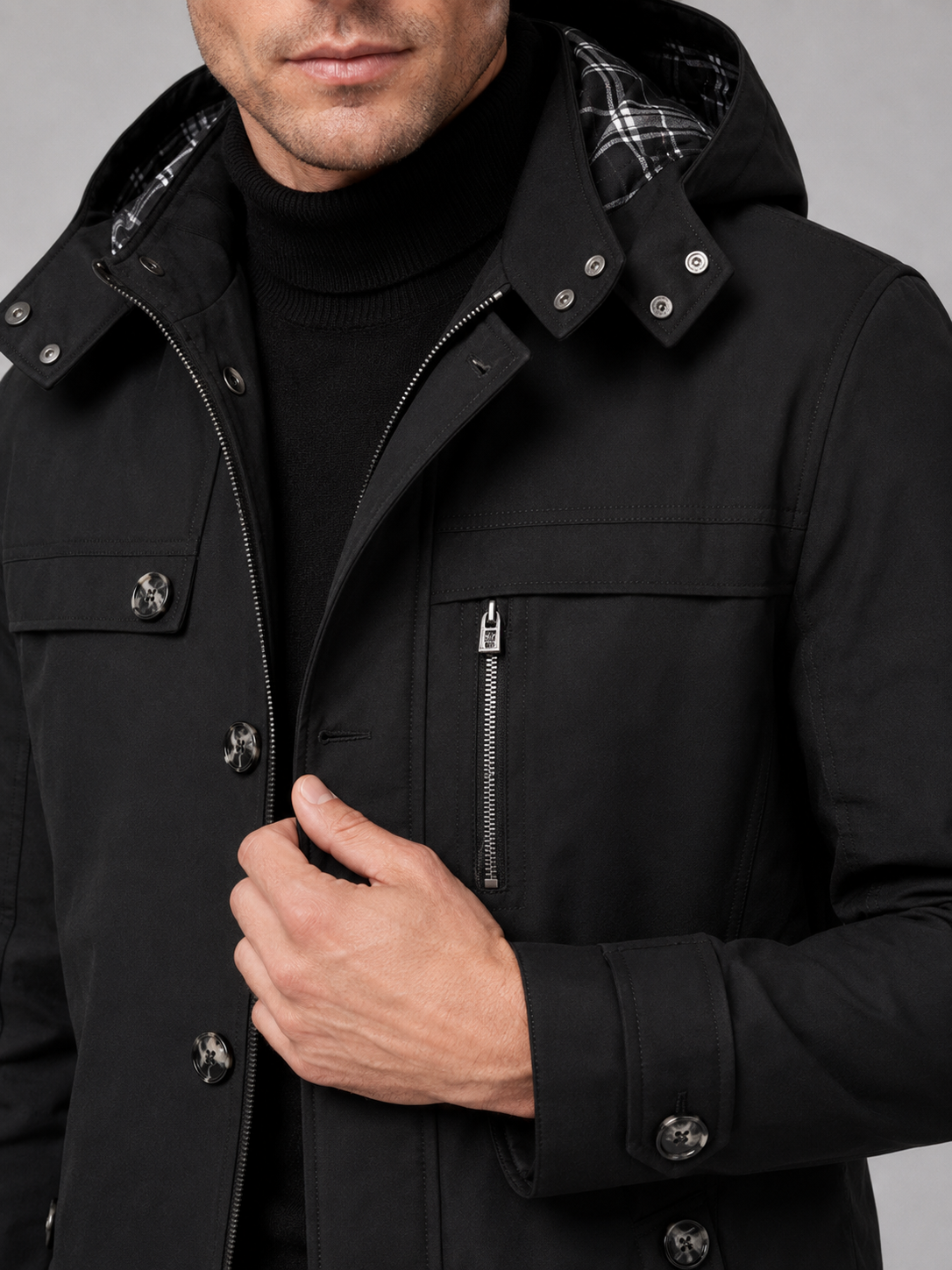 Close up of black hooded trench coat showing thick cotton fabric, attached hood, and button front detail