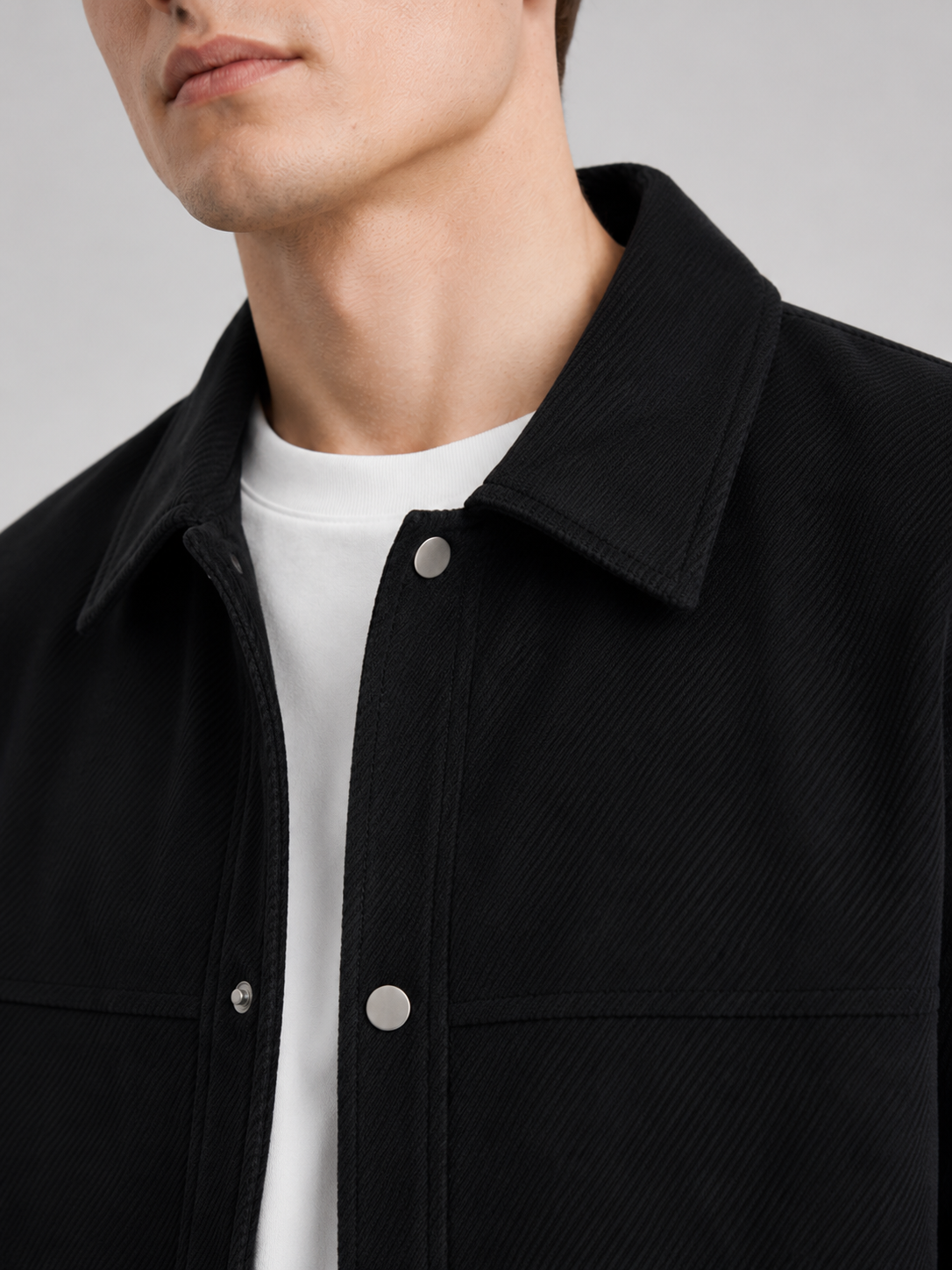 Close up of black corduroy jacket showing soft ribbed texture, classic lapel, and button front detail