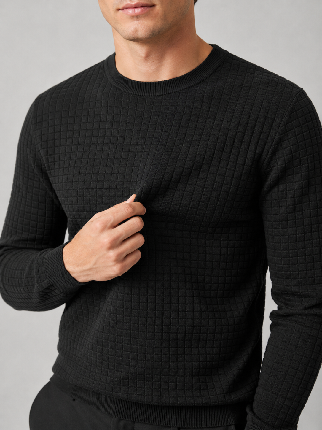 Close up of black jacquard sweater showing textured knit pattern and classic crew neck detail